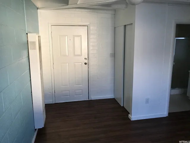 Entry area with wood-finish flooring, a white paneled door, and built-in sliding closet doors