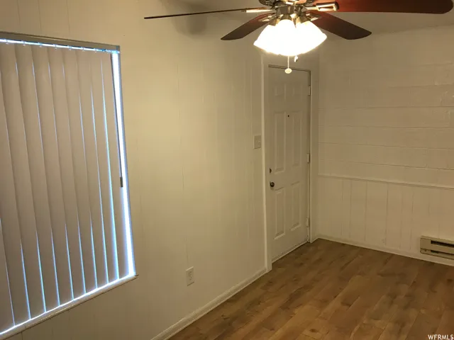 Interior space featuring wood-finish flooring, a ceiling fan with integrated lighting, and a white paneled door