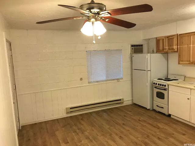 Open-concept living space with wood-finish flooring, ceiling fan with integrated lighting, a full-size refrigerator, white electric range, and wood cabinetry