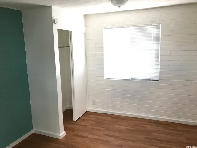 Interior space featuring wood-finish flooring and a white painted brick wall