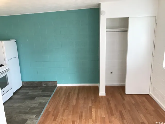 Open concept space featuring wood-finish flooring, a vibrant blue accent wall, and an integrated closet with sliding doors