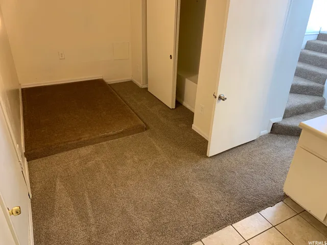 Carpeted landing area featuring an integrated storage platform, a built-in closet with bi-fold doors, and neutral wall finishes