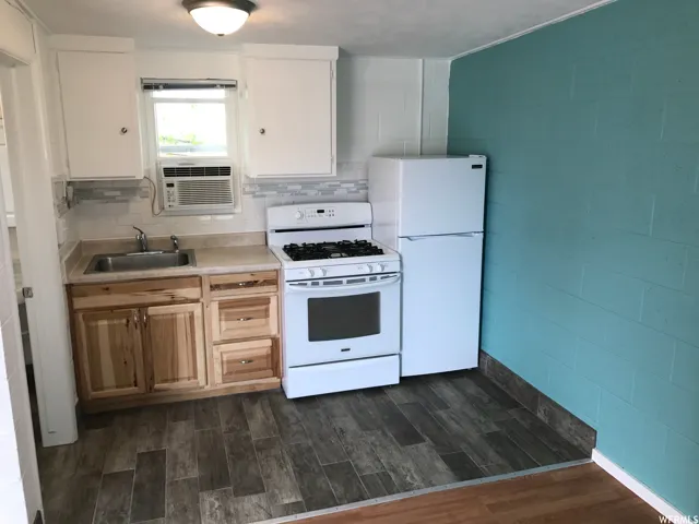 Kitchen featuring wood-finish flooring, white cabinetry, and a gas range