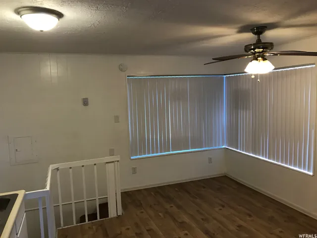 Room featuring wood-finish flooring, vertical blinds on multiple windows, and a ceiling fan with integrated lighting