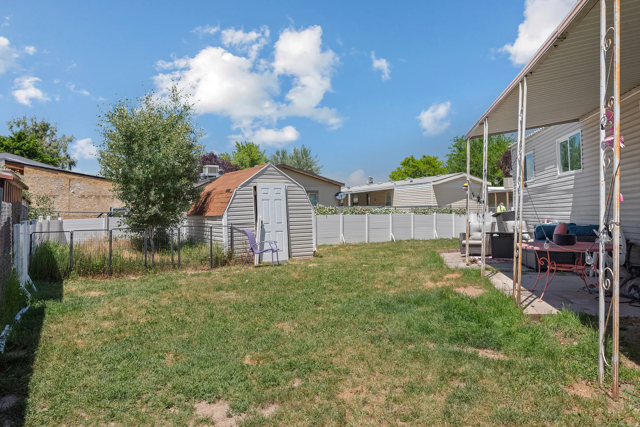 Expansive backyard featuring a covered patio, a storage shed, and a privacy fence