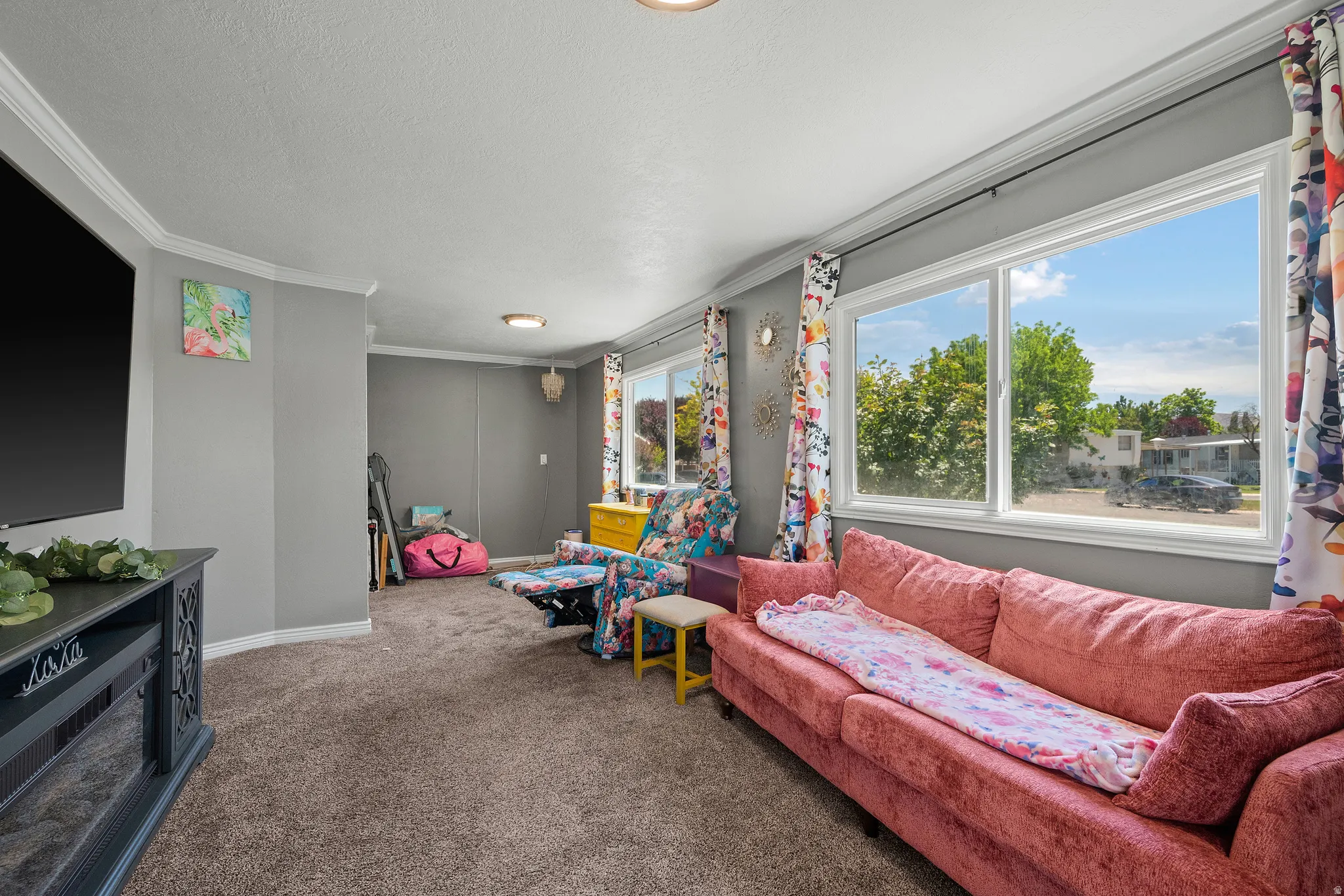 Living-room area with carpet flooring, light gray wall paint, white crown molding and a large window