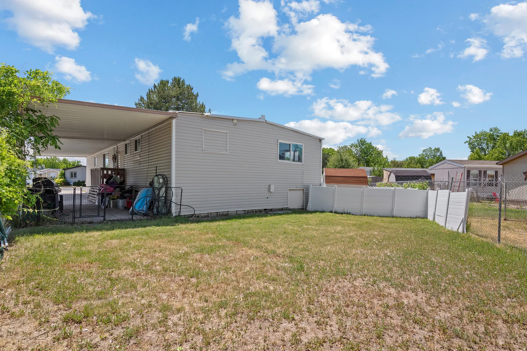 Expansive grassy yard with a white privacy fence and chain-link fencing