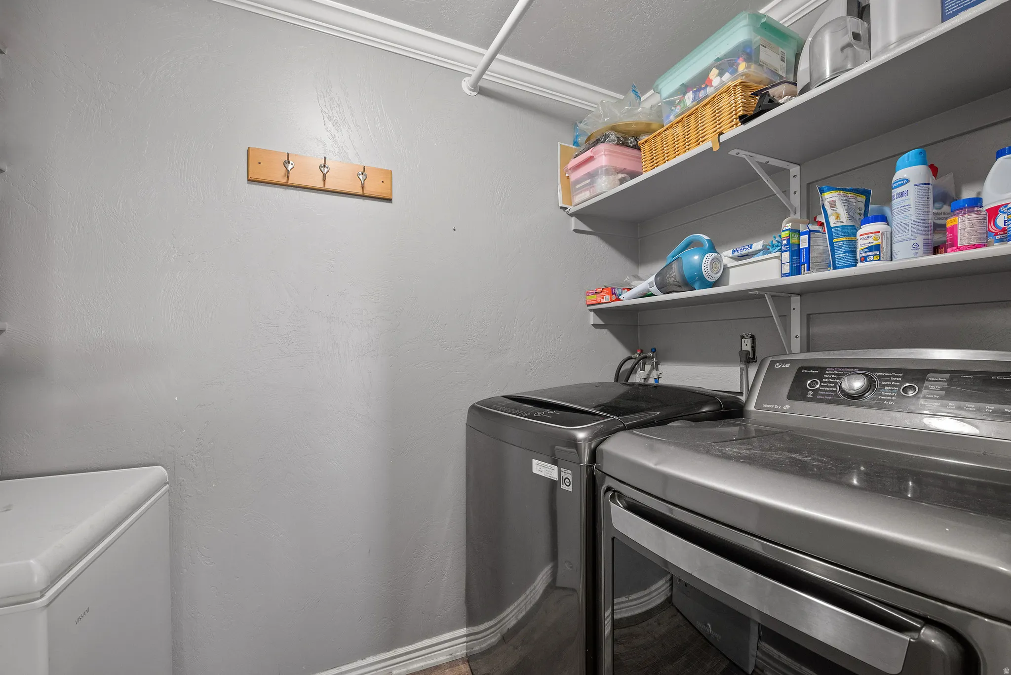 Dedicated utility space featuring wall-mounted shelving, crown molding, and a four-hook rack