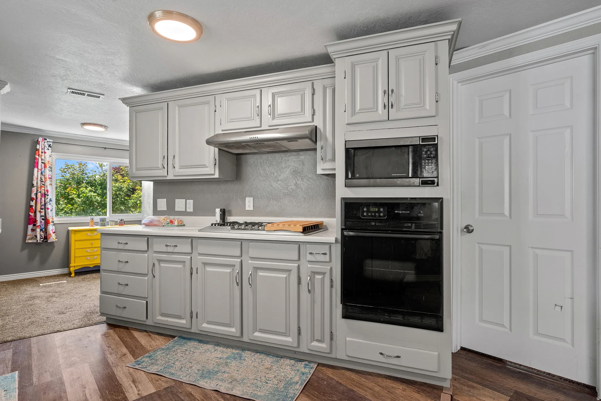 Kitchen featuring painted cabinetry, integrated microwave, built-in oven, gas cooktop, and wood-finish flooring