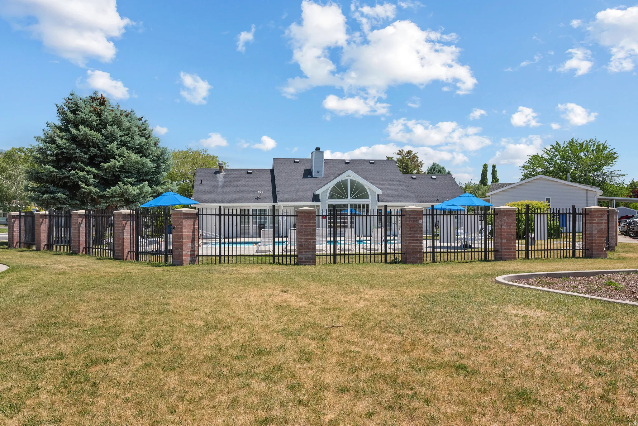 Pool area enclosed by a black metal fence featuring brick pillars