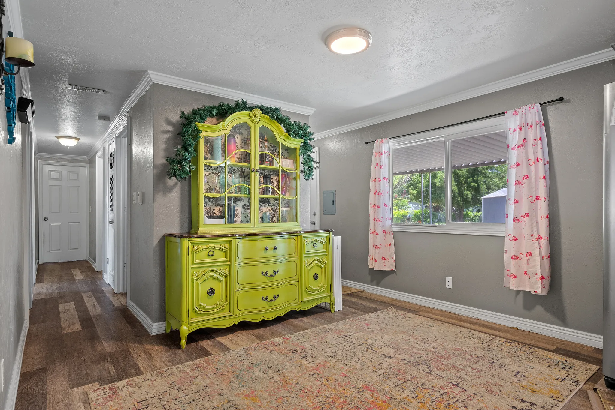 Interior space featuring wood-finish flooring, light gray walls, white baseboards, and crown molding