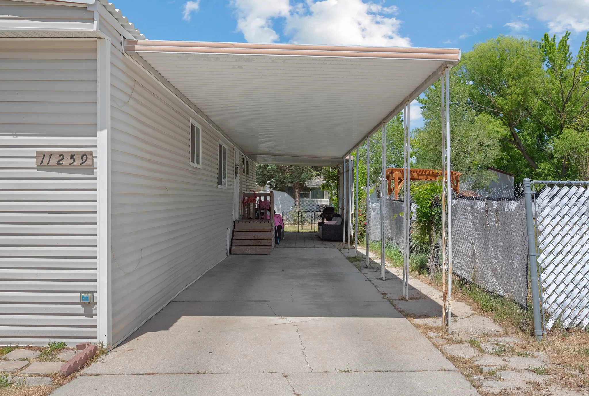 Covered Carport with a concrete drive, siding exterior, and chain link fencing