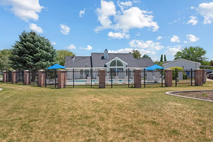 Pool area enclosed by a black metal fence featuring brick pillars