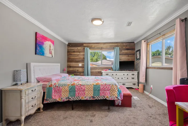 Bedroom featuring a wood-panel accent wall and two windows