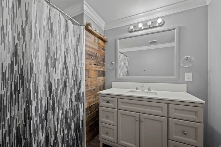 Bathroom featuring a single vanity with a white countertop and undermount sink, framed mirror, and a four-bulb vanity light fixture