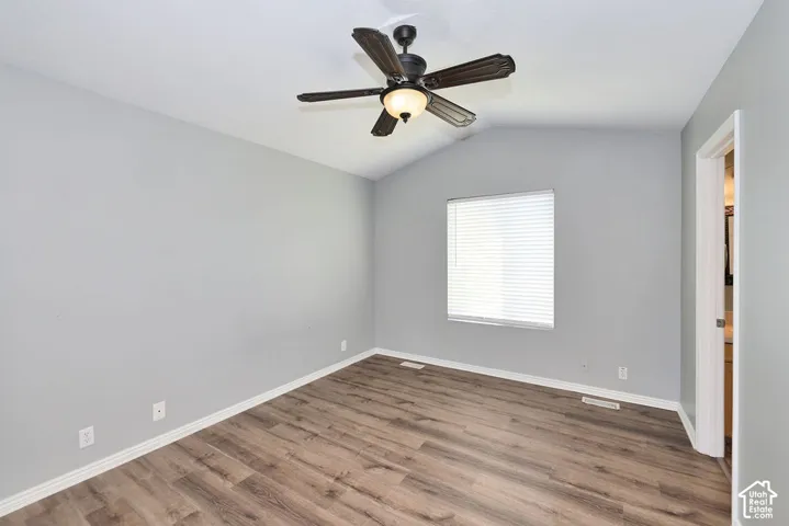 Interior room featuring wood-finish flooring, light gray walls, and a vaulted ceiling
