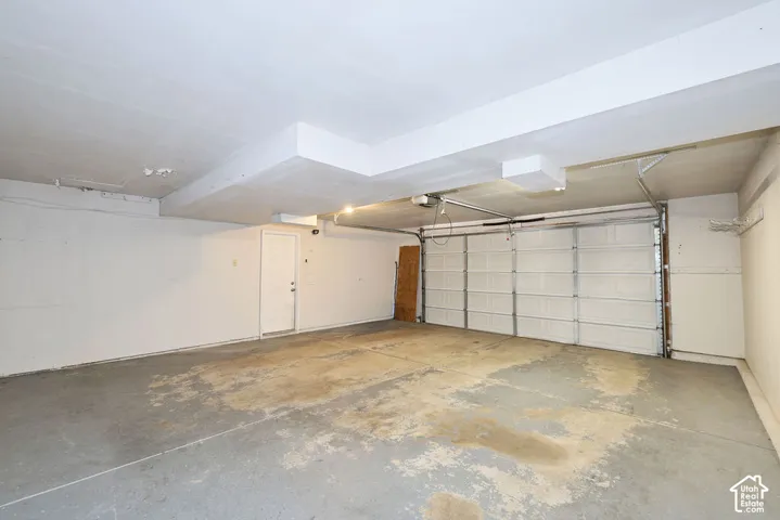 Spacious garage featuring a concrete floor, overhead lighting, and a white paneled garage door