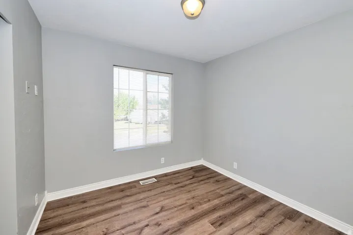Bright room featuring wood-finish flooring, light grey walls, and white baseboards