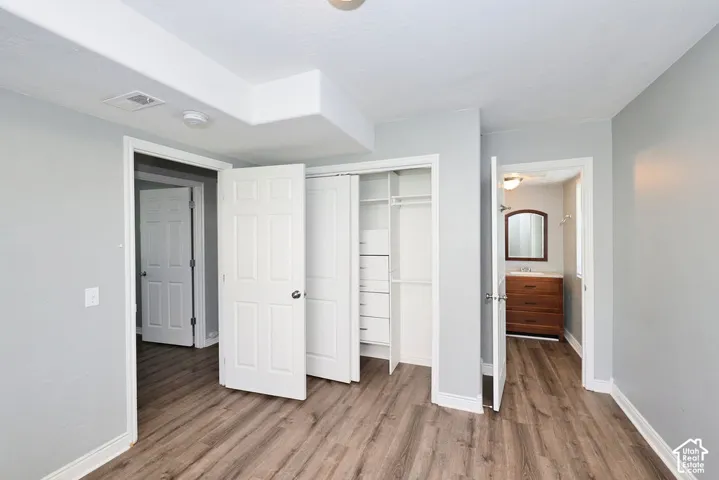 Room featuring wood-finish flooring, light gray wall paint, and white baseboards