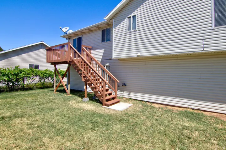 Rear exterior featuring a spacious wood deck and staircase