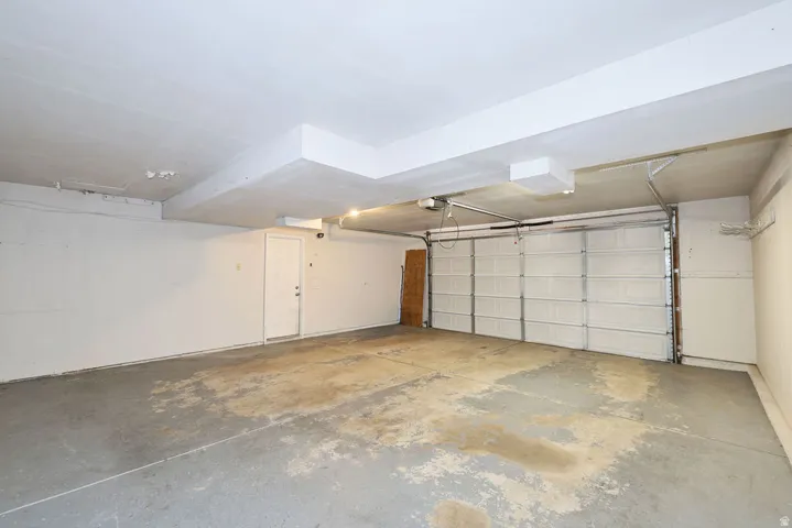 Spacious garage featuring a concrete floor, overhead lighting, and a white paneled garage door