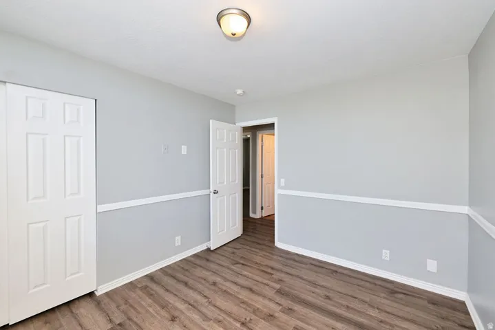 Spacious room featuring wood-finish flooring, two-tone wall paint, white trim, and a ceiling-mounted light fixture