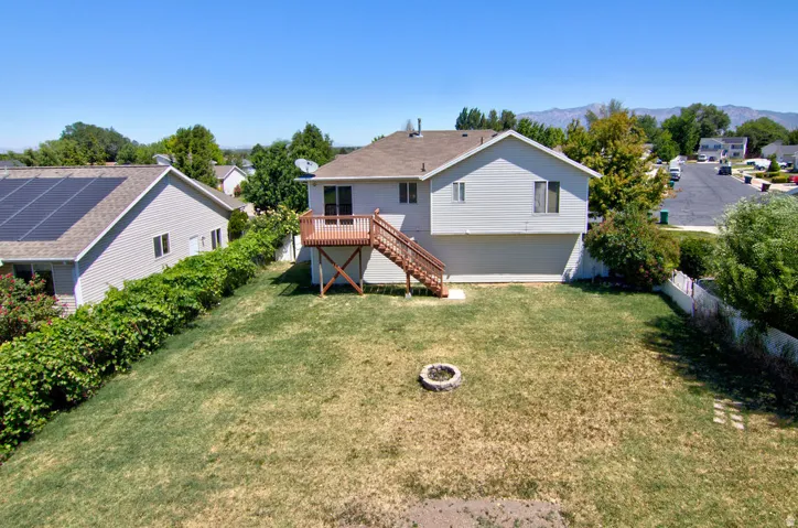 Expansive backyard featuring a deck with natural wood railing and stairs, a built-in fire pit, and partial fencing