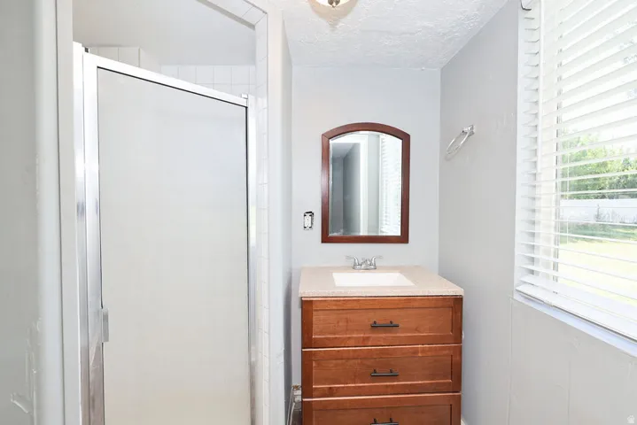 Bathroom with a wood-finish vanity featuring three drawers and a light-toned countertop
