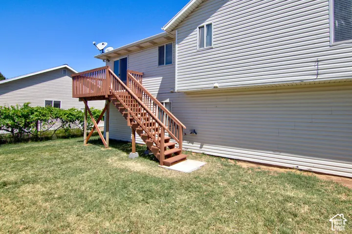Rear exterior featuring a spacious wood deck and staircase