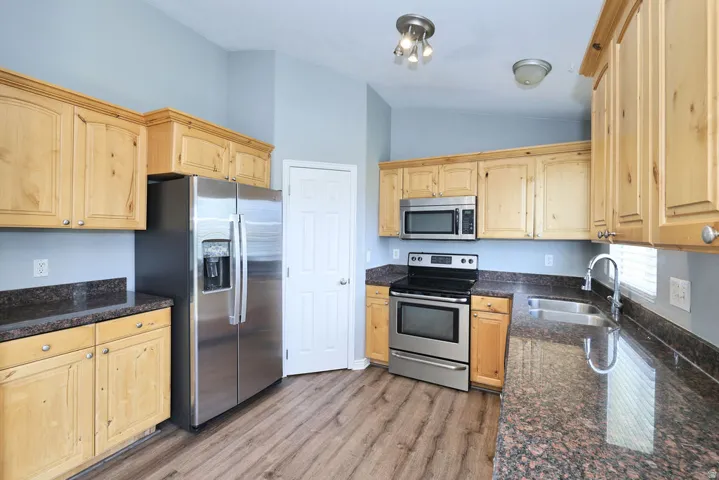 Kitchen featuring wood-finish cabinetry, dark speckled countertops, and stainless steel appliances