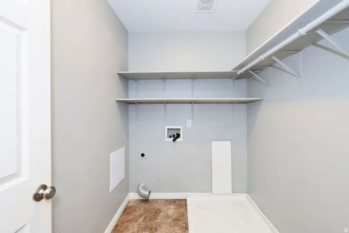 Utility space with neutral wall paint and a combination of tile and unfinished flooring
