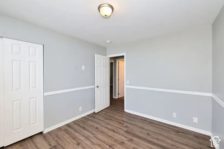 Spacious room featuring wood-finish flooring, two-tone wall paint, white trim, and a ceiling-mounted light fixture