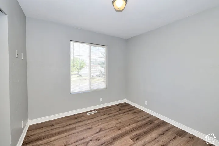 Bright room featuring wood-finish flooring, light grey walls, and white baseboards