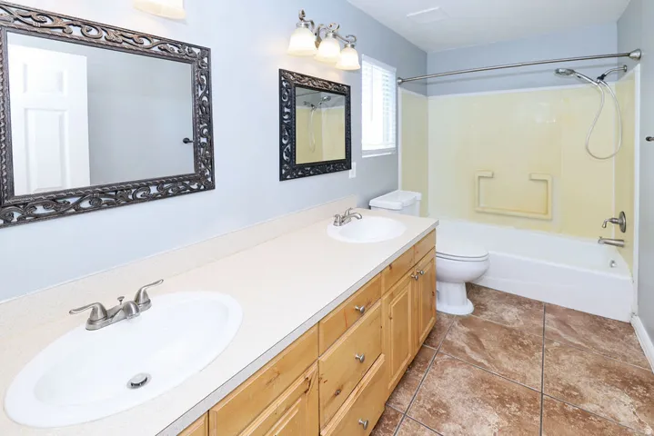 Dual vanity with integrated sinks, light wood-finish cabinetry, and framed mirrors