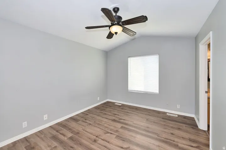 Interior room featuring wood-finish flooring, light gray walls, and a vaulted ceiling