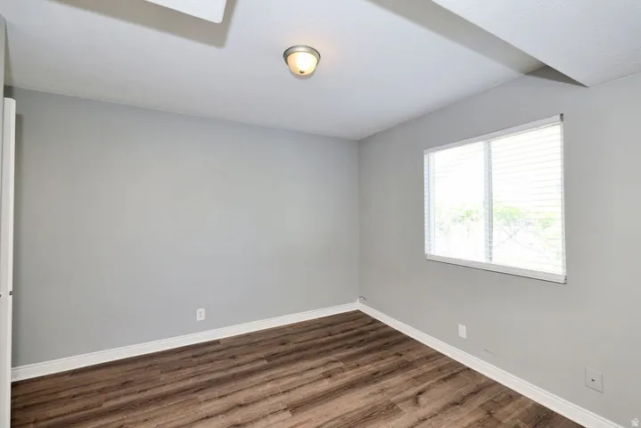 Neutral gray walls featuring wood-finish flooring and white baseboards