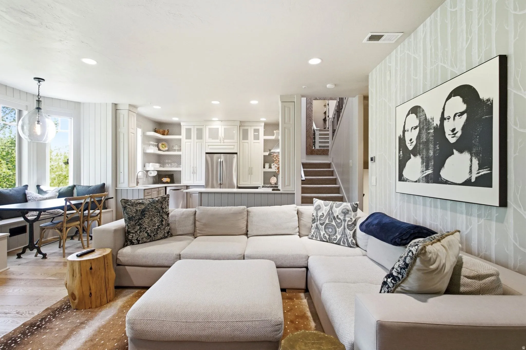 Open-concept living area featuring wood-finish flooring, recessed lighting, and a built-in banquette dining space with large windows