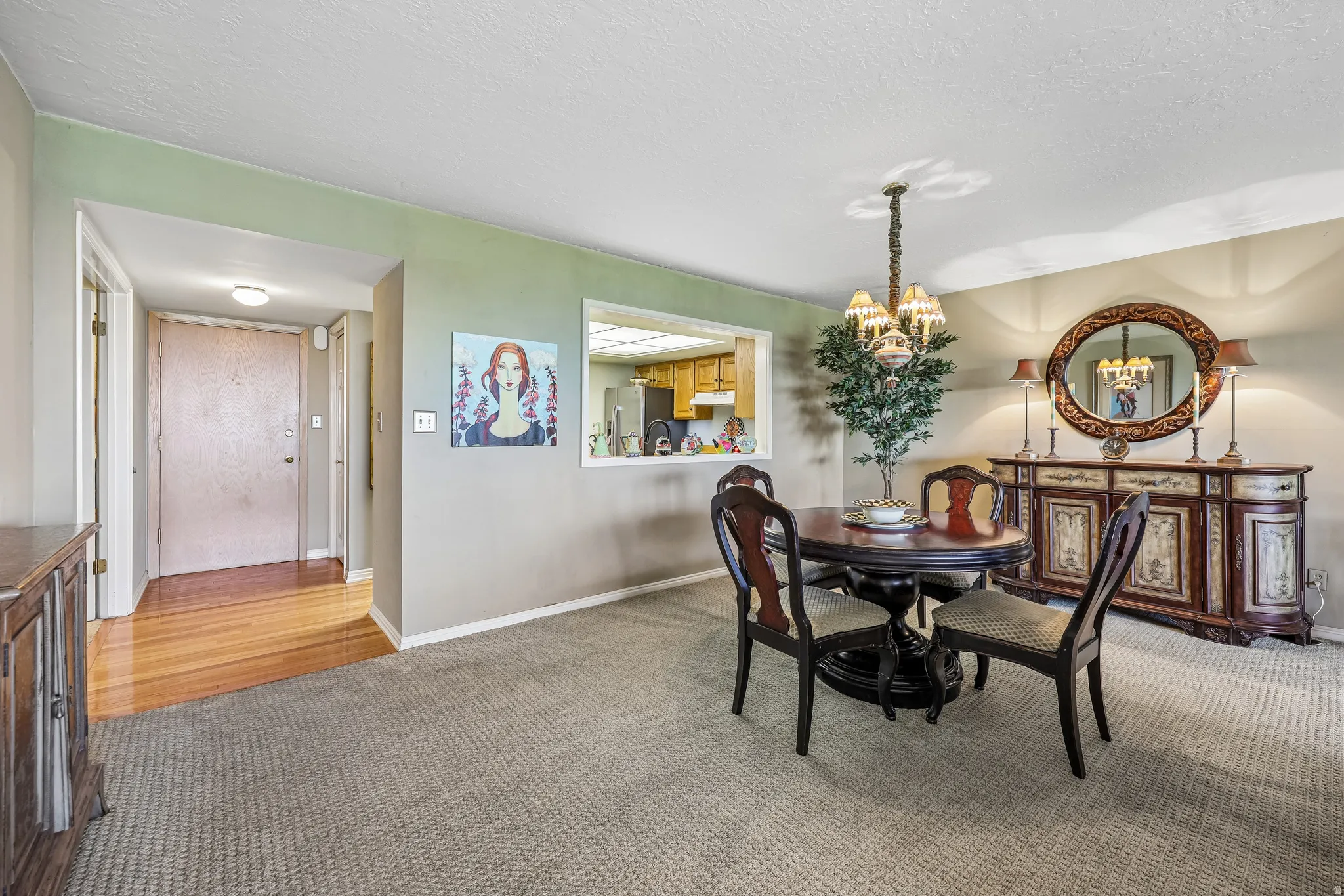 Carpeted dining area featuring a pass-through window, a recessed ceiling light, and a prominent hallway entrance with wood-finish flooring