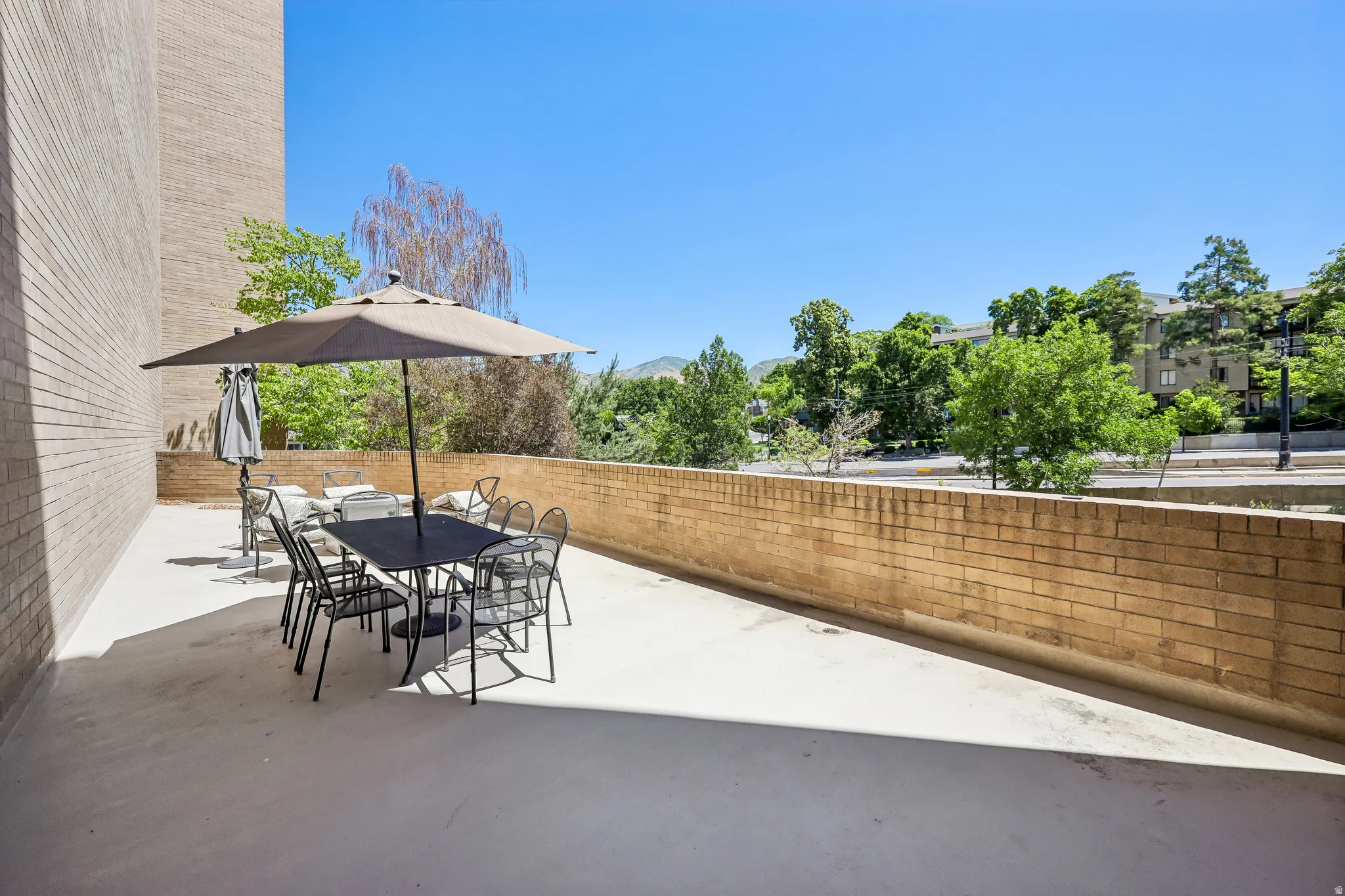 Spacious outdoor patio with a concrete surface and a partial brick privacy wall
