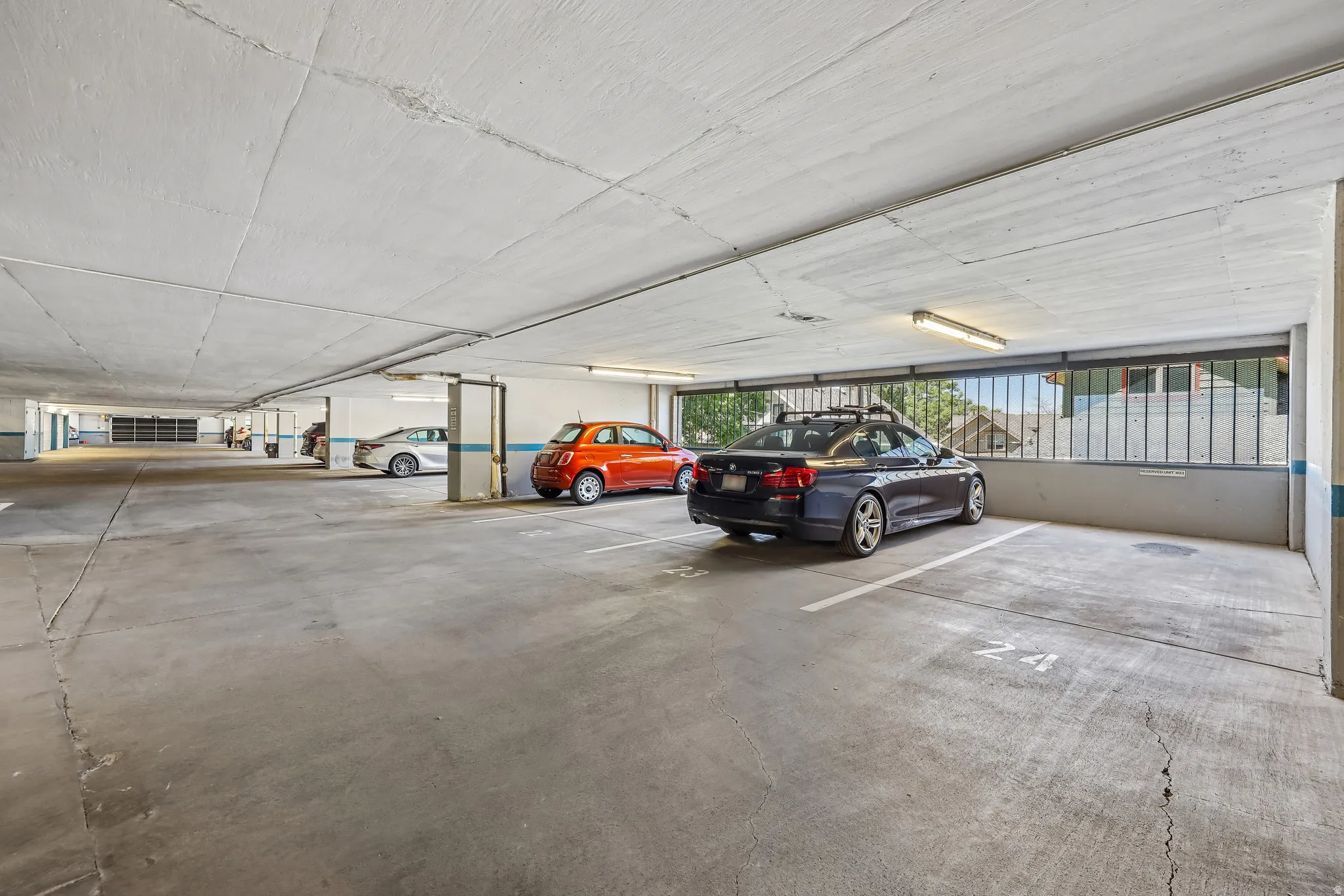 Covered parking garage featuring concrete flooring, structural columns, and integrated lighting