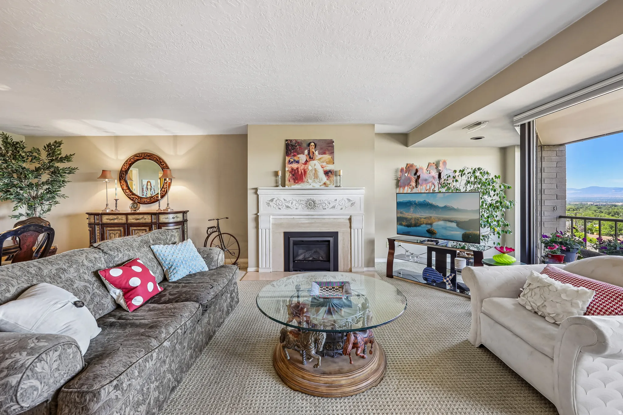 Living area featuring a detailed fireplace with an ornate mantel, a glass sliding door providing access to an exterior balcony, and light-toned carpeting