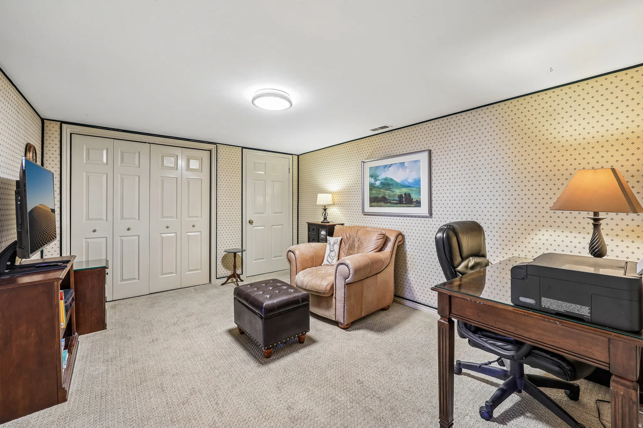 Carpeted room featuring light-colored bi-fold doors and a single panel door, with textured wallpaper and a flush-mount ceiling light