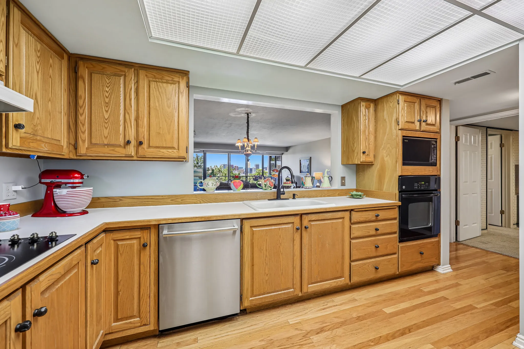 Kitchen featuring wood-finish flooring, wood cabinetry, white countertops, and a pass-through window