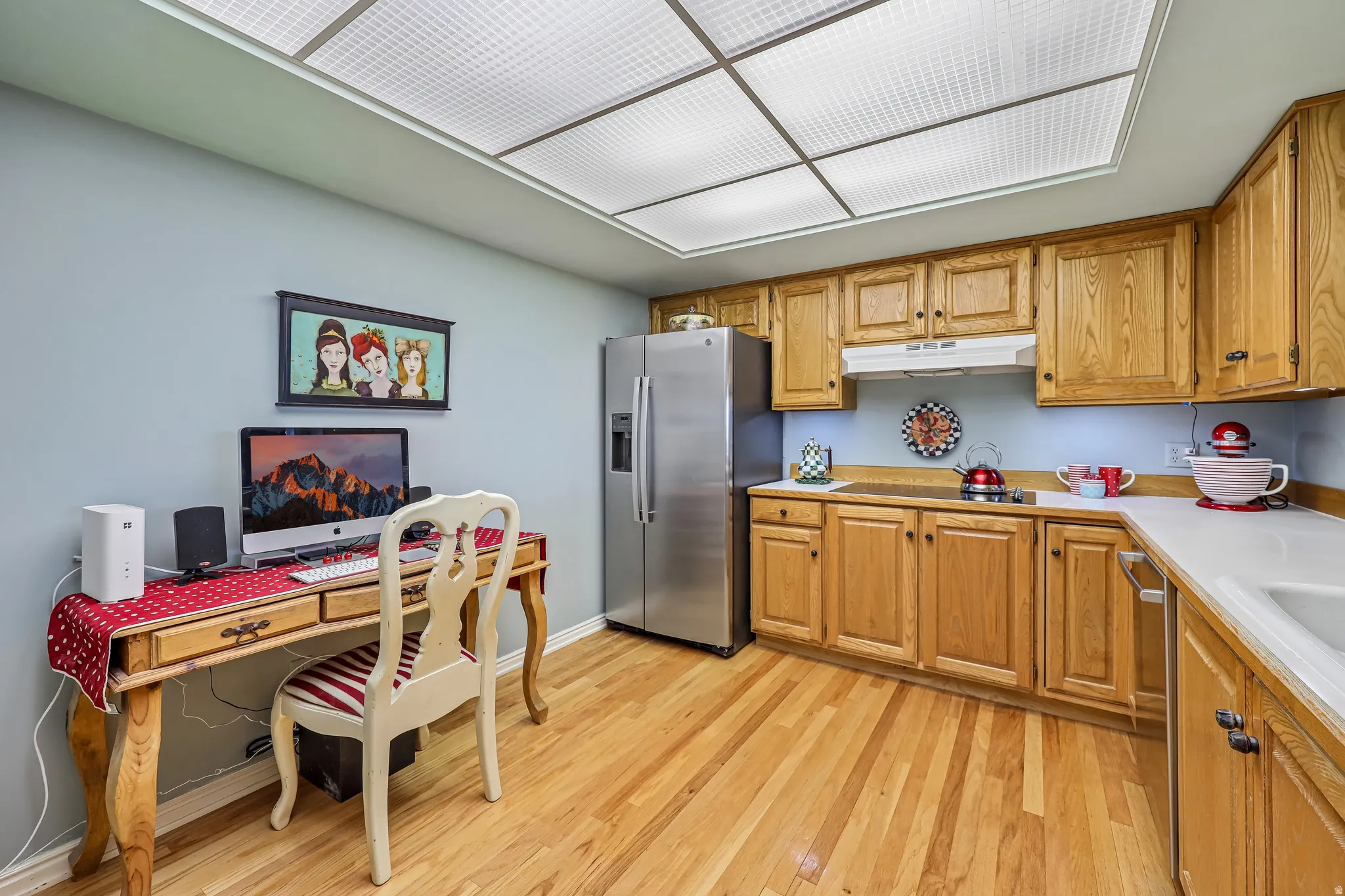 Kitchen featuring wood-finish flooring, light wood cabinetry, white countertops, and a full suite of stainless steel appliances