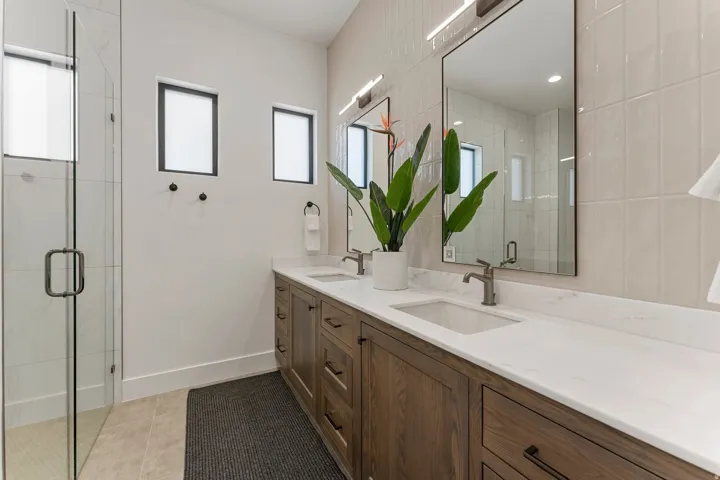 Double vanity featuring wood-finish cabinetry and integrated rectangular sinks with bronze-finish fixtures