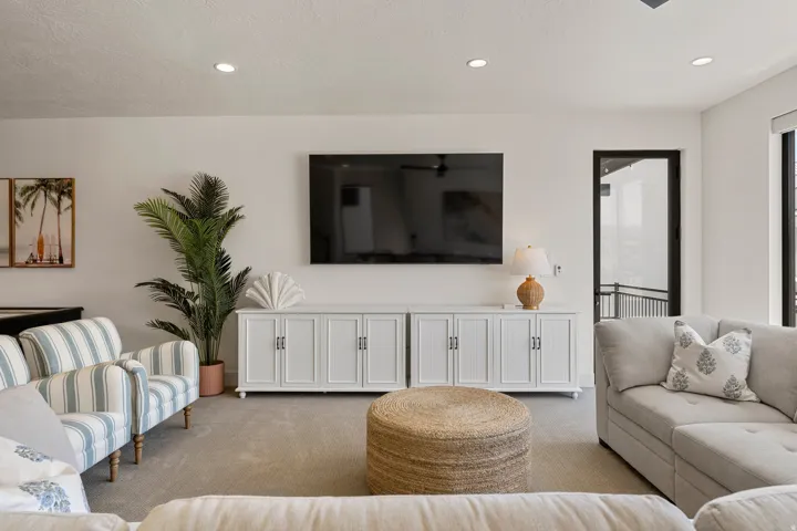 Living area featuring recessed lighting, a built-in media console, a wall-mounted television, and a glass-paned door leading to an outdoor space