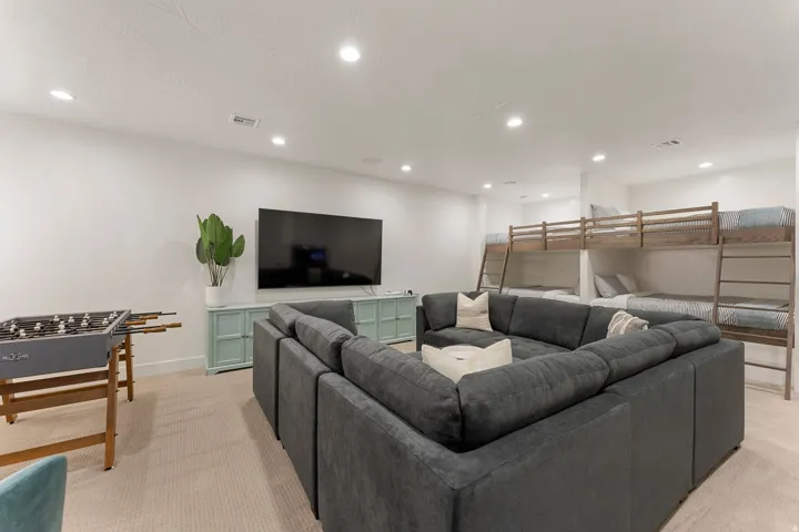 Spacious recreation room featuring recessed lighting, light-colored carpeting, a built-in entertainment console, and integrated bunk beds