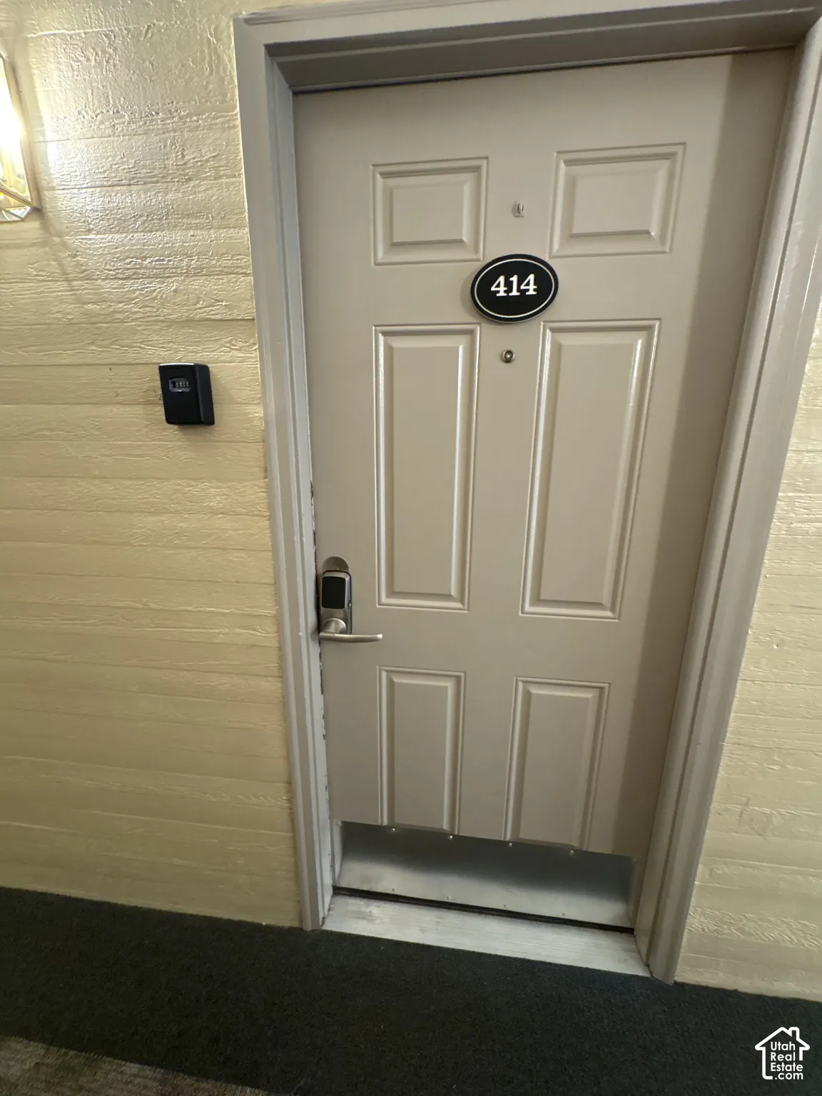 Entry door with panel detailing, featuring a digital keypad lock and a prominent numeric address plaque