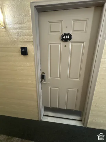 Entry door with panel detailing, featuring a digital keypad lock and a prominent numeric address plaque