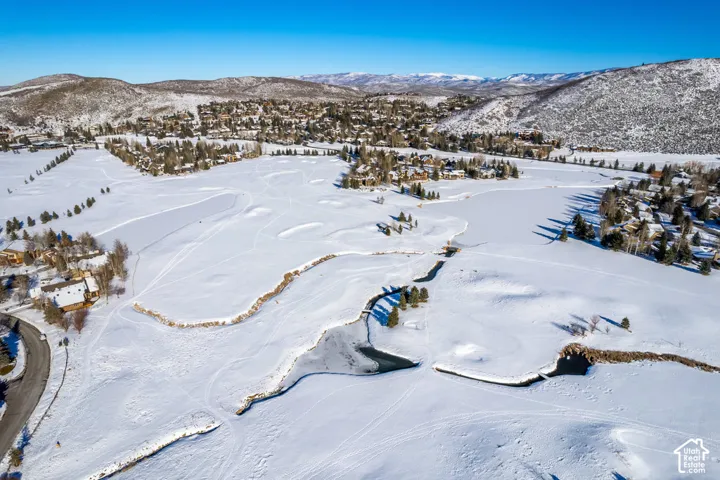 Expansive winter landscape featuring snow-covered terrain, a frozen waterway, and distant mountainous backdrops